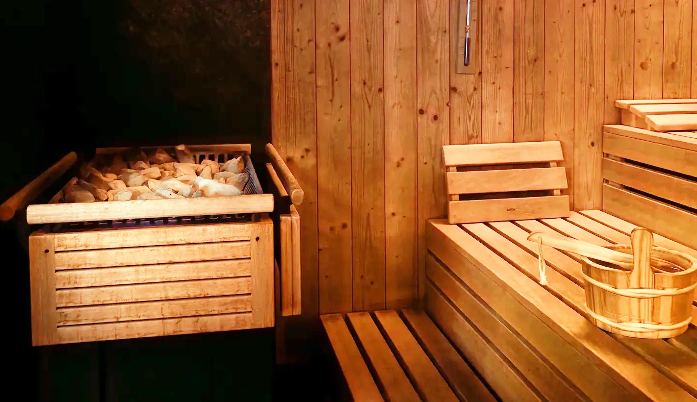 Saunaofen mit Steinen, Holzbänke und Holzkübel in der Finnischen Sauna