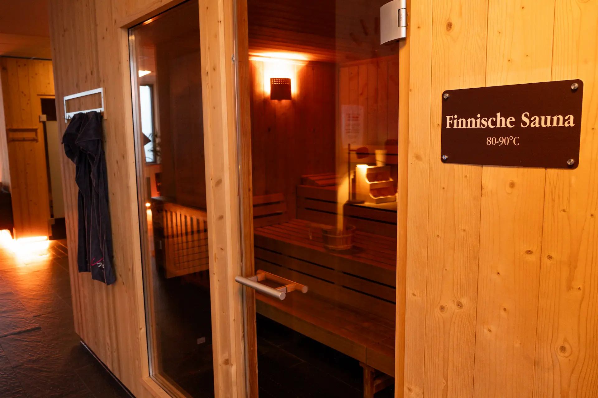 Holztür der Finnischen Sauna mit Schild, warm beleuchtet